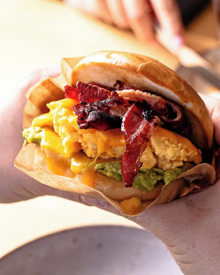 Mão a segurar o Bag’all, com ovo mexido, bacon e abacate