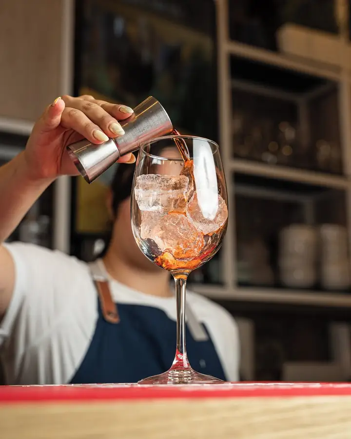 Barman a servir um cocktail num copo de vinho com gelo